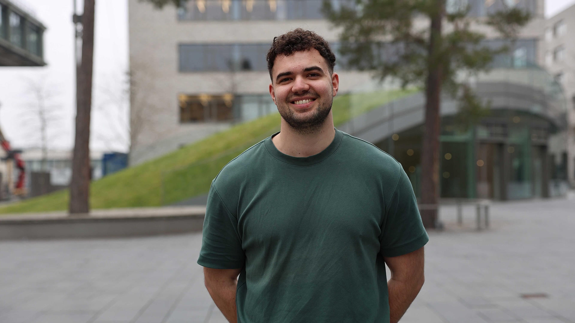 Auf dem Foto sieht man den neuen Studenten Leon Müller im grünen T-Shirt vor der Mensa am Bildungscampus in Heilbronn 