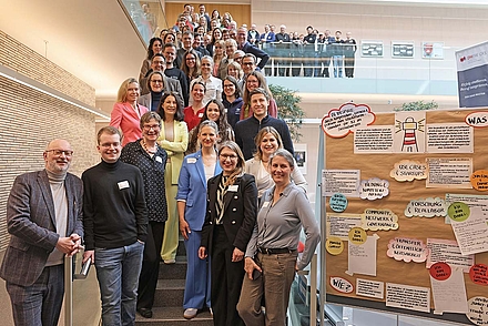 Die Teilnehmer*innen des Zukunftstags stehen auf einer Treppe, neben ihnen steht eine Metaplanwand, welche die Projektgruppen benennt